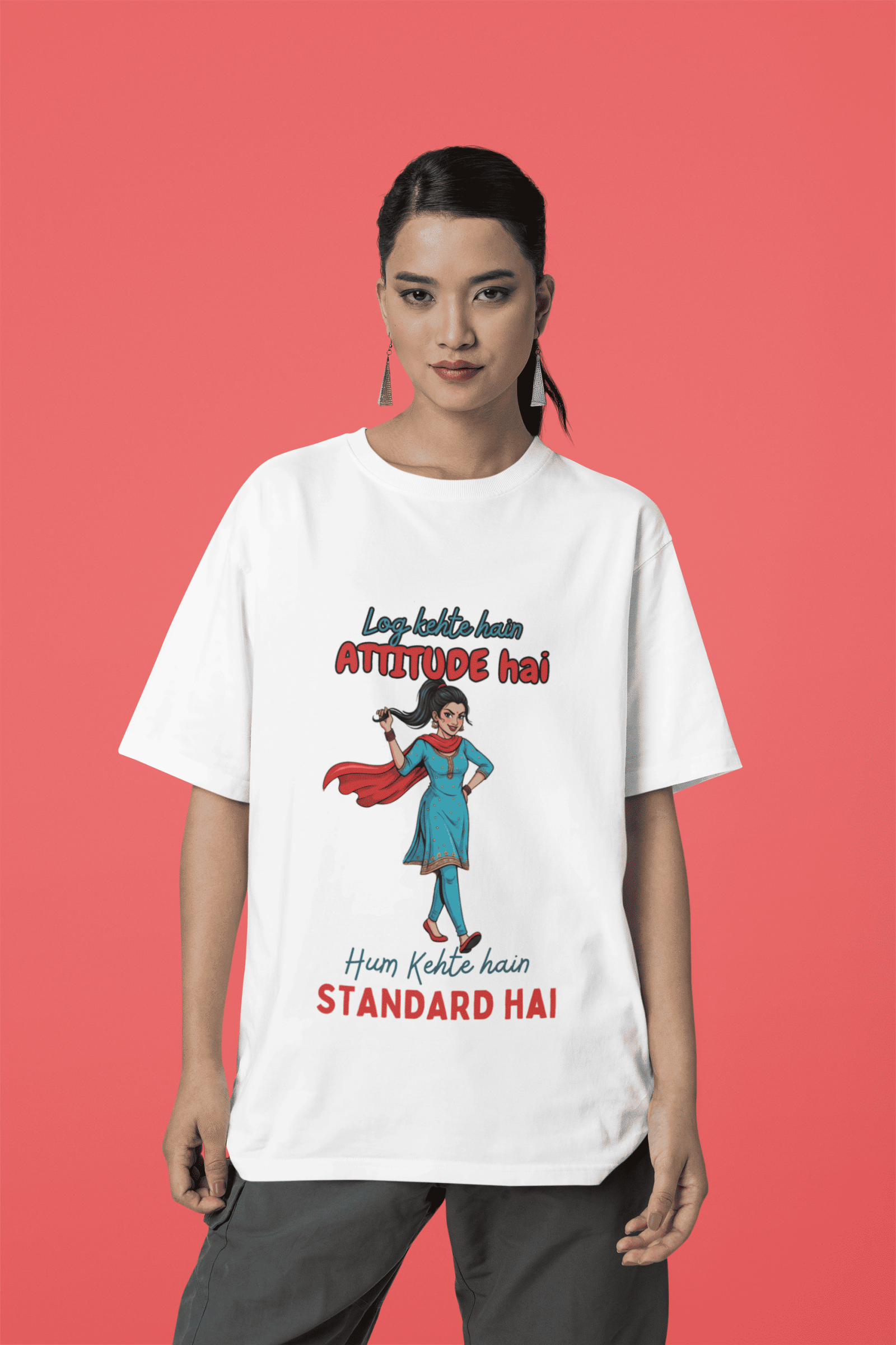 White Desi Swag Oversized Tee by PodLyft. A classic white t-shirt featuring a vibrant print of a Desi girl and a bold attitude quote, posed against a red background.