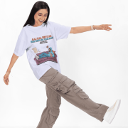 Lavender Modern Beti Oversized T-shirt – Zero Kaam Attitude Edition by PodLyft. A smiling model poses dynamically in a light purple oversized graphic tee paired with cargo pants.